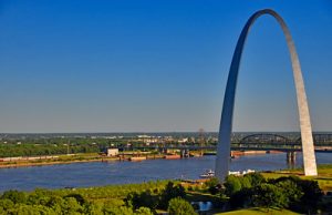 The St. Louis Arch beside the Mississippi River with blue sky.