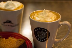 a pair of white coffee mugs containing coffee with frothy milk in dim lighting