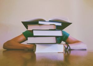 Image of a pile of books with a person behind books.